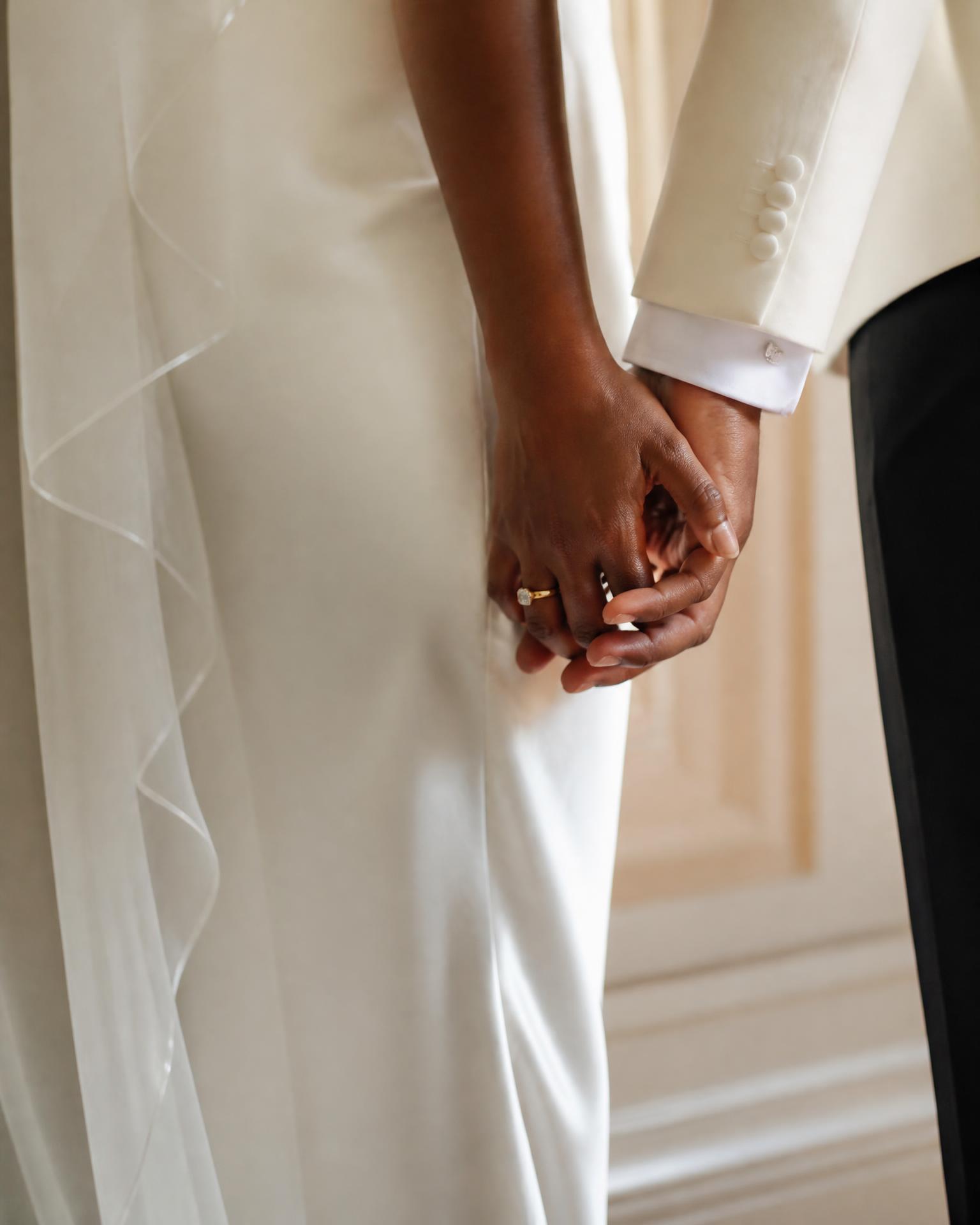 A newlywed couple holding hands, styled in ivory and black